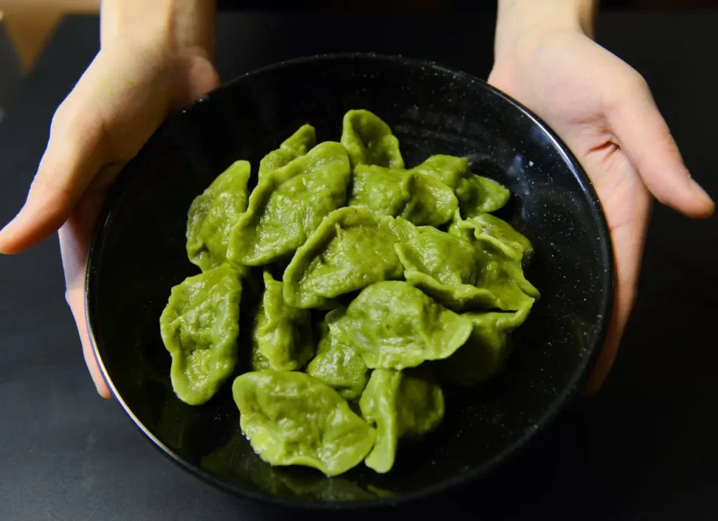 Image of green raw leaves in pan catching by hand