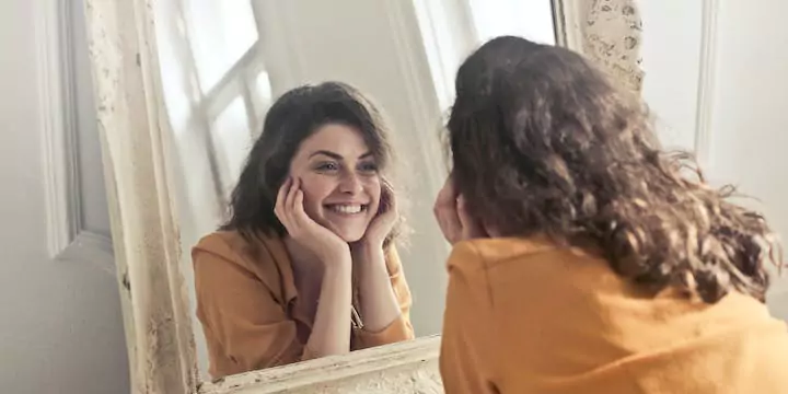 a girl looking her face on mirror